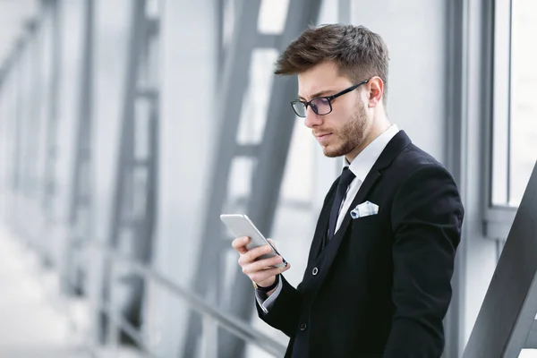 Hombre de negocios urbano serio mensajes de texto en el teléfono celular en el aeropuerto — Foto de Stock