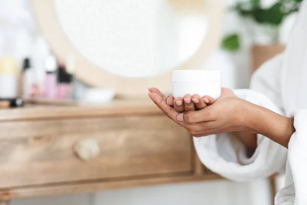 Nutrición de la piel. irreconocible mujer africana sosteniendo tarro con crema hidratante en las manos —  Fotos de Stock