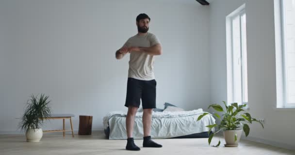 Jonge man met baard training thuis, opwarmen — Stockvideo