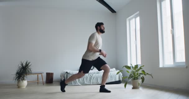 Bearded man gör lungor övningar för benet hemma — Stockvideo