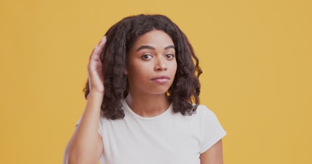 Nieuwsgierig zwart meisje hand in hand dicht bij haar oor en luisteren rond zorgvuldig — Stockvideo
