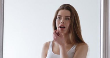 Güzel bir kadın ruj sürüyor, büyük aynaya yansıyor.