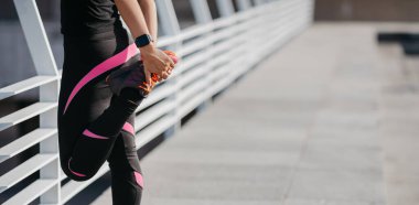 Açık hava ve egzersiz yaşam tarzı konsepti. Spor giyimli spor ayakkabılı bir kız bacak kasları için ısınıyor.