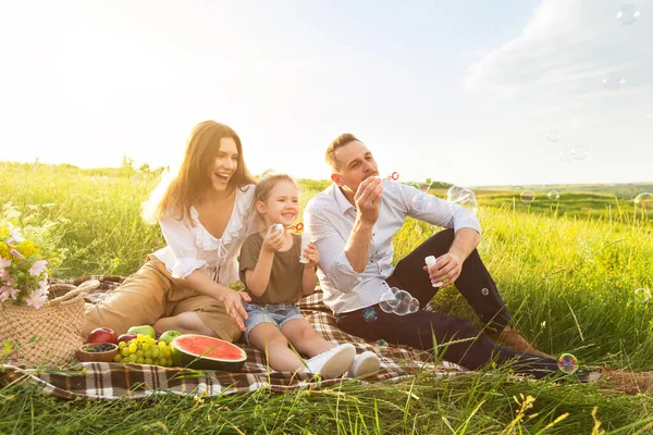Симпатичная семья из трех человек играет вместе на пикнике — стоковое фото