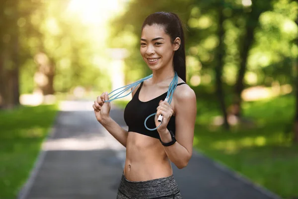 Fit lächelnde Asiatin posiert mit Springseil im Freien — Stockfoto