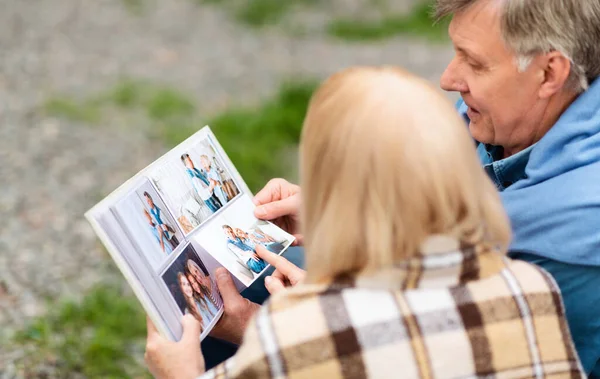 Gemeinsame glückliche Erinnerungen. Senior-Mann blättert mit Frau im Freien in Fotoalbum — Stockfoto