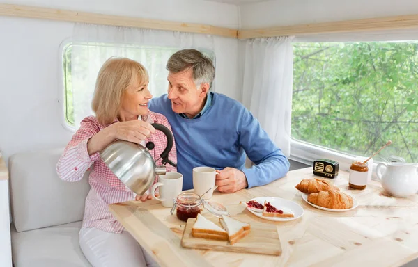 Liebevolle Frau gießt ihrem Mann während des Frühstücks im Wohnmobil Tee ein, freier Platz — Stockfoto