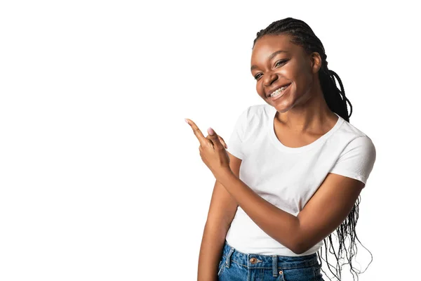 Afrikai lány fogszabályzó mutató ujját félre, fehér háttér — Stock Fotó