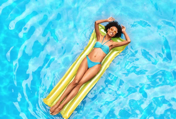 Vacaciones de verano. Chica negra milenaria relajándose en lilo en la piscina al aire libre en el día soleado, vista superior —  Fotos de Stock