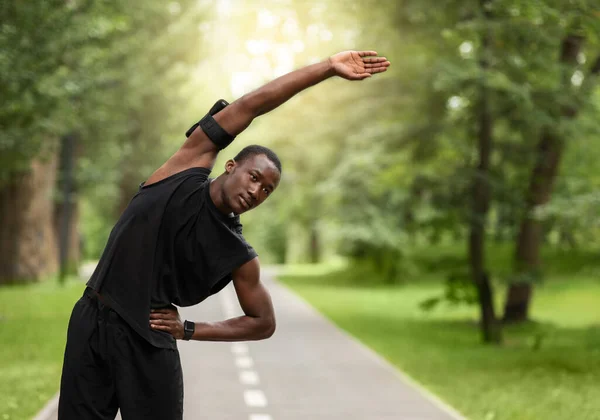Athletischer Schwarzer dehnt sich vor dem Training im Park — Stockfoto