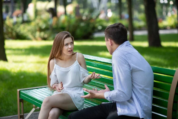 Проблемы в отношениях. Миллениальная пара спорит на скамейке в летнем парке — стоковое фото