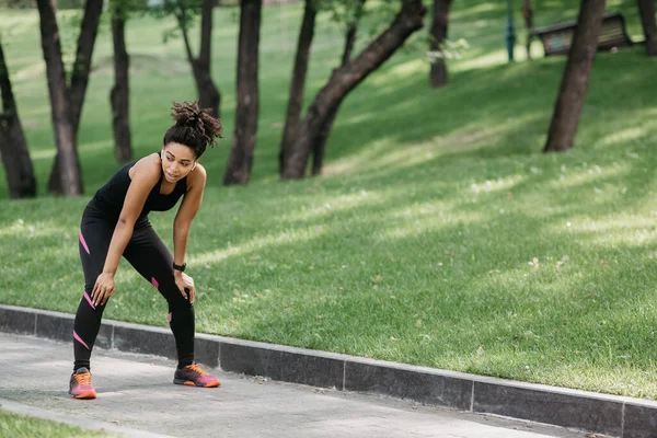 Respira mientras trotas. Chica cansada en ropa deportiva con rastreador de fitness y auriculares —  Fotos de Stock