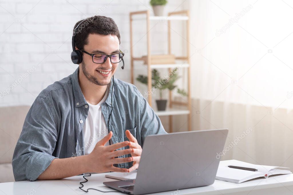 Conversation with client and video call. Guy with glasses and headset gesticulating with hands and watching laptop