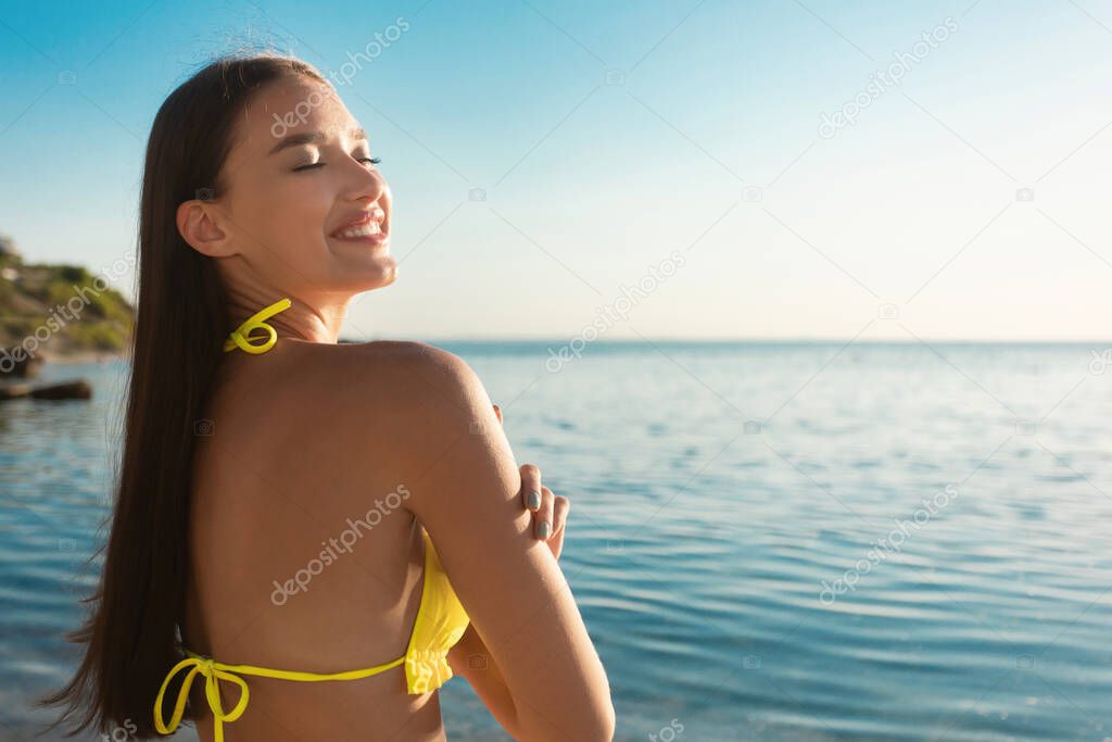 Tanned Girl In Swimwear Sunbathing At Seaside Standing On Beach