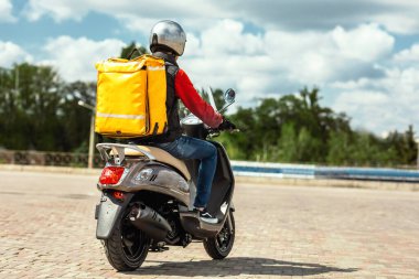Sırt çantalı kurye Scooter 'a biniyor. Şehirde yemek dağıtıyor.