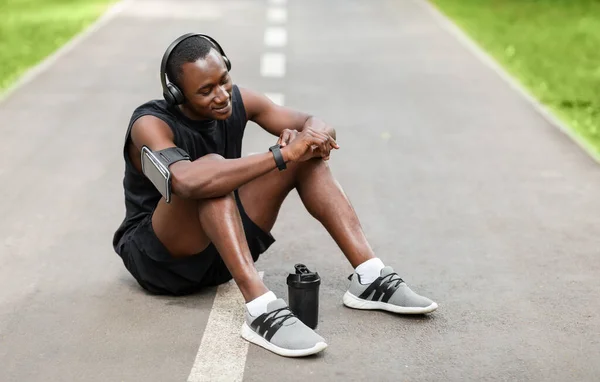 Sportlicher Schwarzer ruht sich aus und benutzt seine Smartwatch — Stockfoto