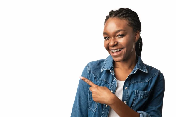 Zwart meisje wijzend vinger opzij over witte studio achtergrond — Stockfoto