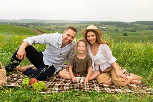 Счастливая молодая семья проводит время вместе на пикнике — стоковое фото