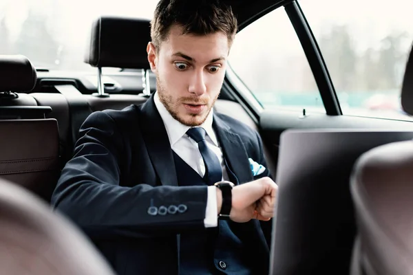 年轻的生意人在车里看着手表 — 图库照片