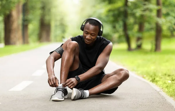 Sportlicher Afrikaner schnürt vor dem morgendlichen Joggen seine Sportschuhe — Stockfoto