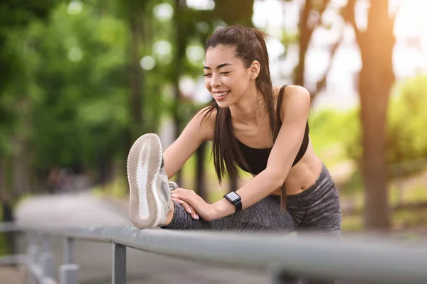 Flessibile asiatico ragazza stretching gamba muscoli mentre lavoro fuori in città parco — Foto Stock