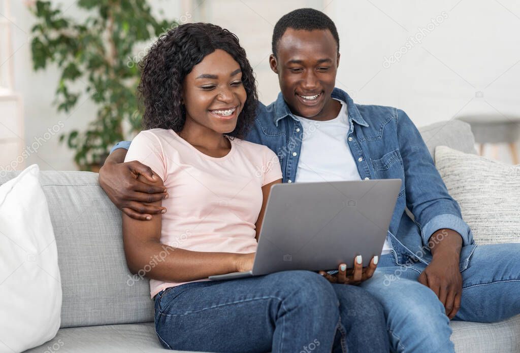Lovely black couple using laptop at living room at home
