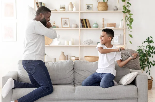 Feliz Tempo Juntos. preto pai travesseiro lutando com preteen filho no casa — Fotografia de Stock