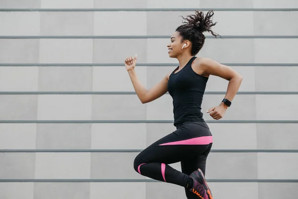 Jogging com música favorita. Africano menina americana com rastreador de fitness, corre — Fotografia de Stock
