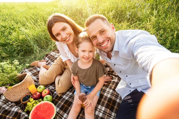 Família feliz tomando selfie no campo no dia ensolarado — Fotografia de Stock