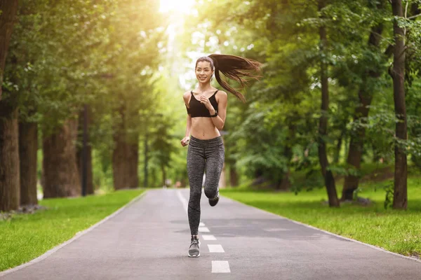 Mañana Deportiva. alegre asiático chica corriendo en camino en ciudad parque — Foto de Stock