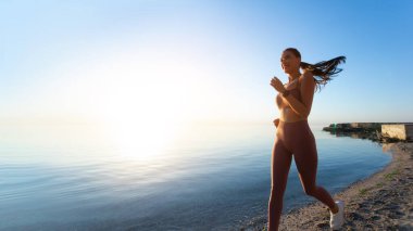 Kumsalda koşan sağlıklı, mutlu kadın.