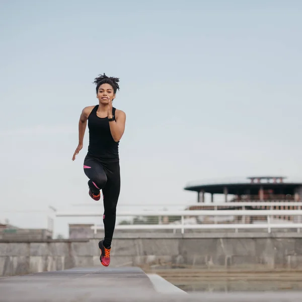 Correndo com saltos no treinamento. Africano menina americana no esporte uniforme no salto, no estádio — Fotografia de Stock