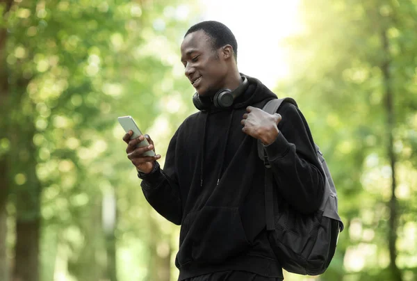 Cara africano feliz usando smartphone, treinamento no parque — Fotografia de Stock