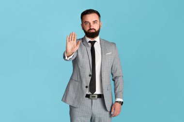 Reddedildi. Resmi giyimde kendine güvenen girişimci mavi arkaplan üzerinde STOP hareketi gösteriyor