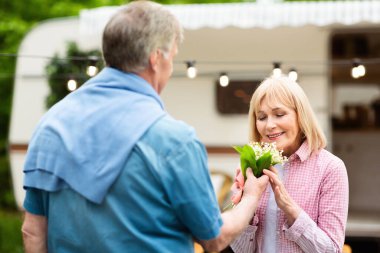 Sevgi dolu olgun koca, sevgili karısına kamp alanında aromatik çiçekler veriyor.
