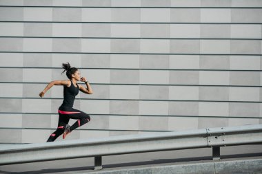 Hızlan ve kaç. Spor giyim sektöründe Afro-Amerikalı bir kız sokakta koşuyor.