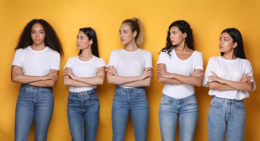 Diverse Women Looking At African Girl Standing Over Yellow Background clipart