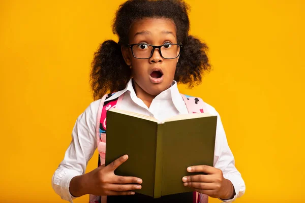 Überraschte Schülerin hält Buch in die Kamera, Studioaufnahme — Stockfoto