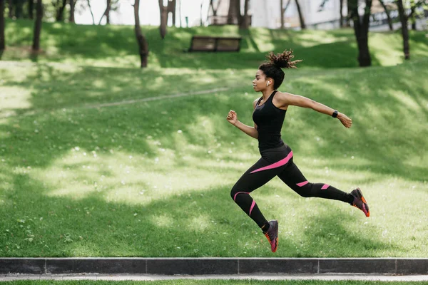 Saltar y correr al aire libre en la naturaleza. Chica en uniforme deportivo congelado en el aire —  Fotos de Stock