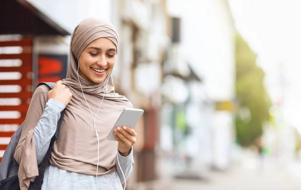 Gyönyörű lány hidzsáb segítségével fülhallgató és okostelefon — Stock Fotó