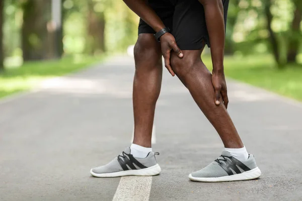 Afričan si třel bolavou nohu, dostal křeč při běhání — Stock fotografie