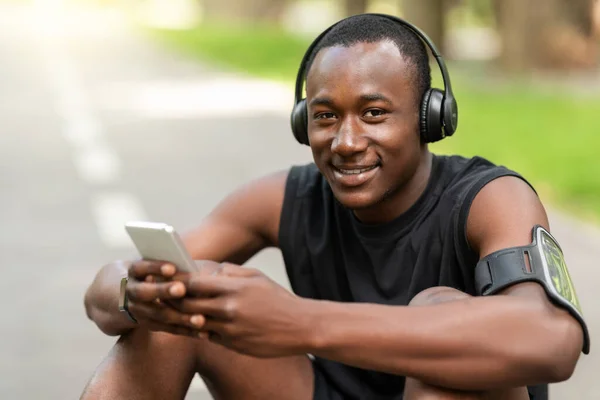 Primer plano del sonriente deportista negro usando el teléfono mientras descansa —  Fotos de Stock