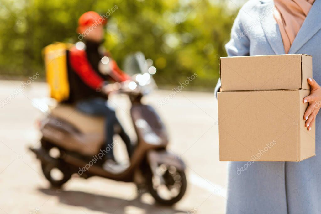 Unrecognizable Woman Holding Boxes Standing Near Courier On Scooter Outdoors
