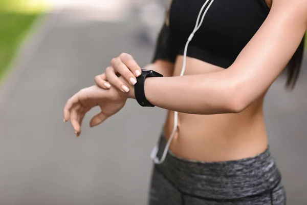 Fechar o ajuste menina verificando smartwatch ou rastreador de fitness durante o treinamento ao ar livre — Fotografia de Stock