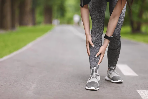 Молодая бегунья, страдающая шинами голени во время пробежки в парке — стоковое фото