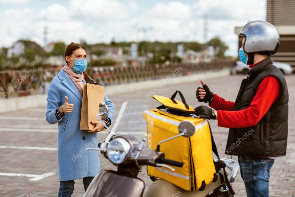 Delivery Courier And Woman In Protective Masks Gesturing Thumbs-Up Outside
