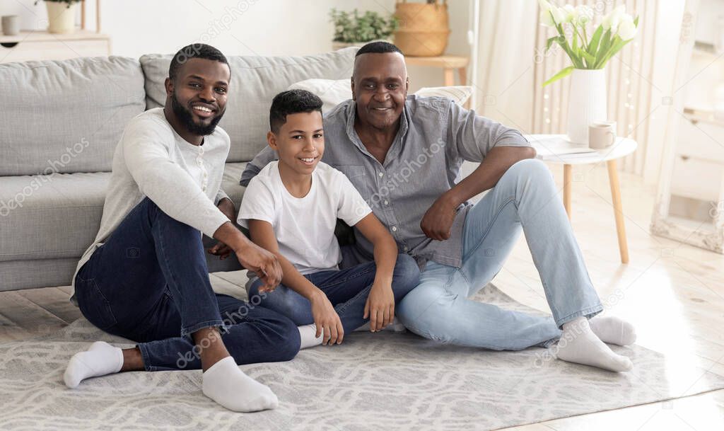 Happy black father, son and grandfather relaxing together on floor at home