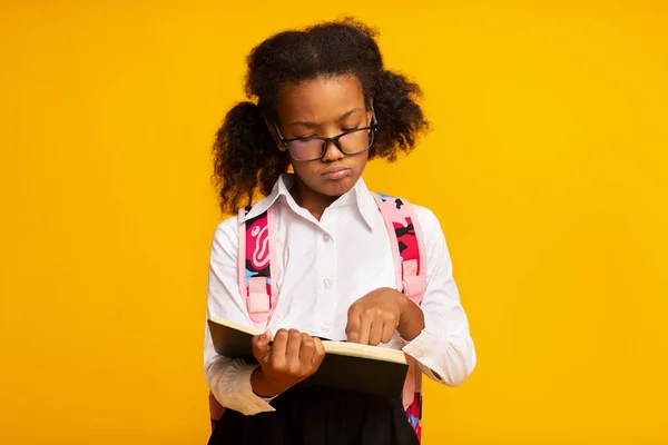 Dyslexic Schoolgirl ανάγνωση βιβλίο στέκεται πάνω από κίτρινο φόντο, Studio Shot — Φωτογραφία Αρχείου