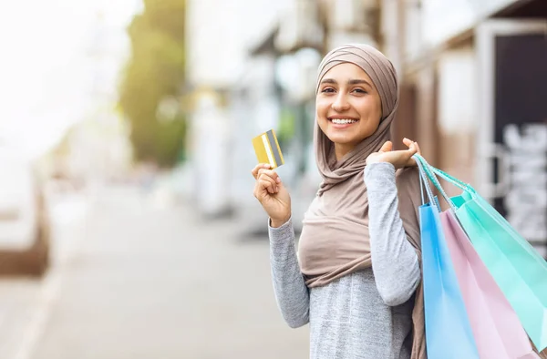 Alışveriş torbalarıyla kredi kartı gösteren heyecanlı müslüman kız. — Stok fotoğraf