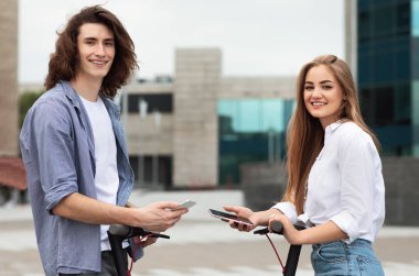 Motorlu motosiklet kullanan, elinde telefon tutan arkadaşlar.